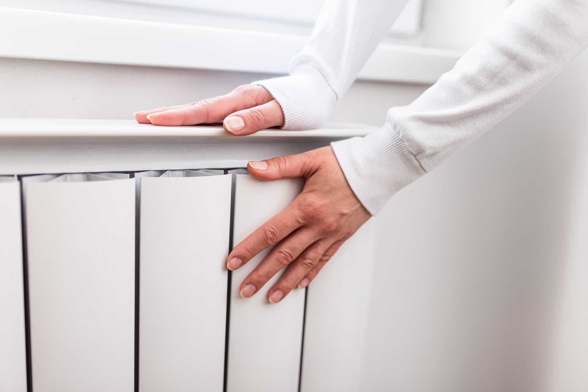Hand resting on a warm white radiator after a central heating installation in Blackpool