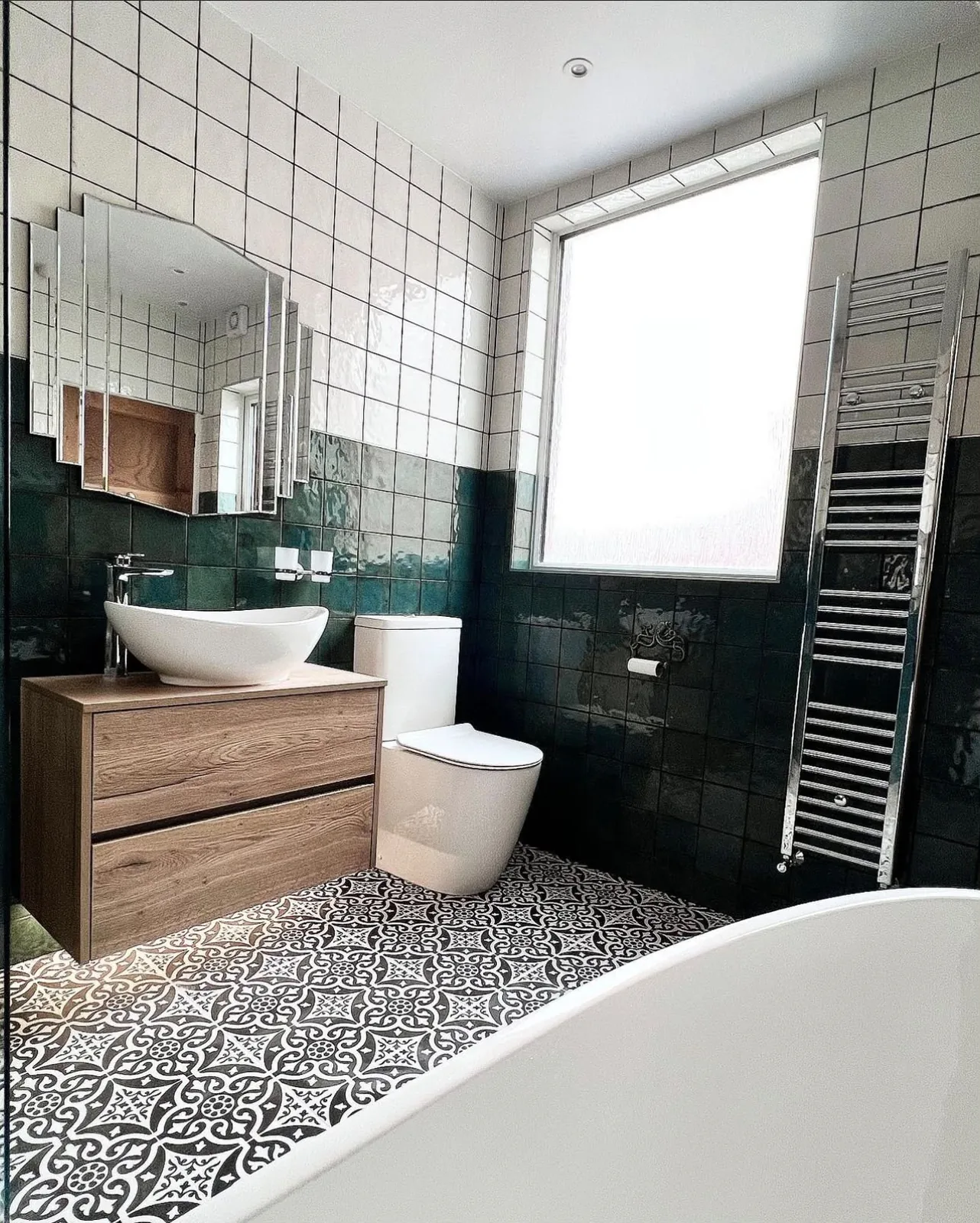 Bathroom renovation with green metro wall tiles, patterned floor tiles and a tall chrome towel radiator